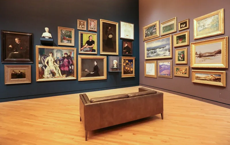 Visitors viewing framed paintings in a gallery hall